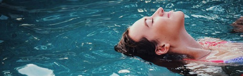 På billedet ses hoved og skuldre af en person, der flyder på vandet.